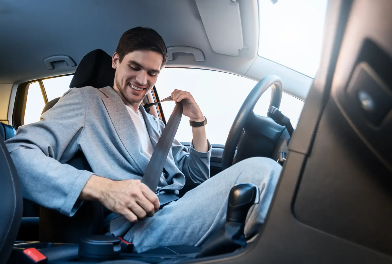 Driver drawing a seat belt across the chest before setting off in a passenger car