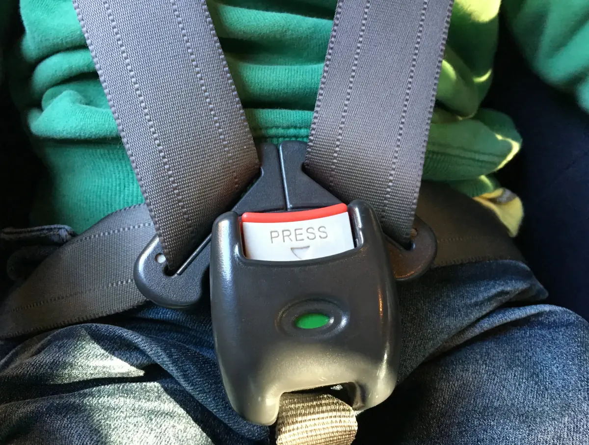 Child harness buckle fastened across an occupant in a rear vehicle seat