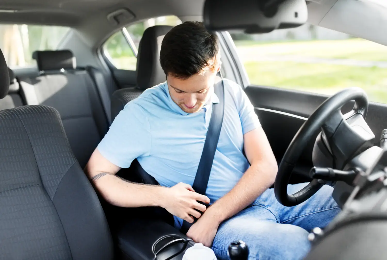 Occupant fastening a three-point seat belt in the front of a passenger car