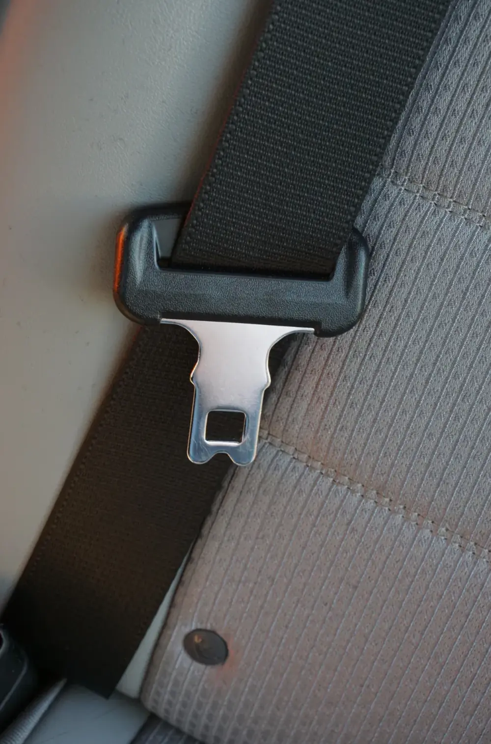 Seat belt webbing threaded through a moulded guide with the tongue plate hanging below it
