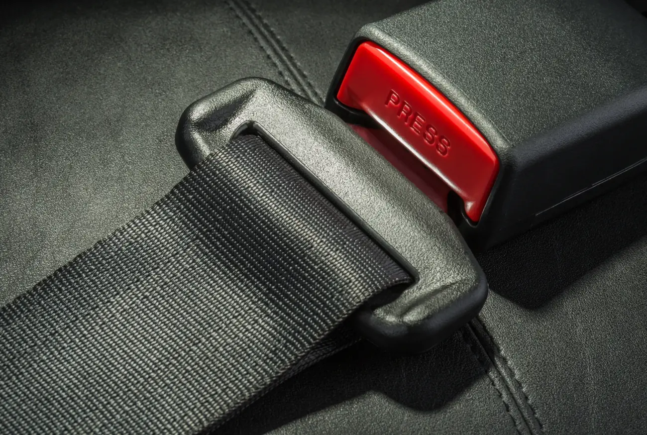 Seat belt tongue plate seated inside its buckle housing with the release button visible